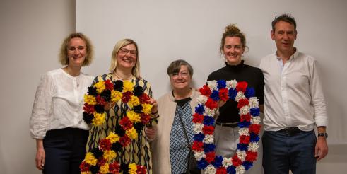 Fünf Personen schauen in die Kamera und halten eine aus Papierblumen gestaltete 20 in die Höhe