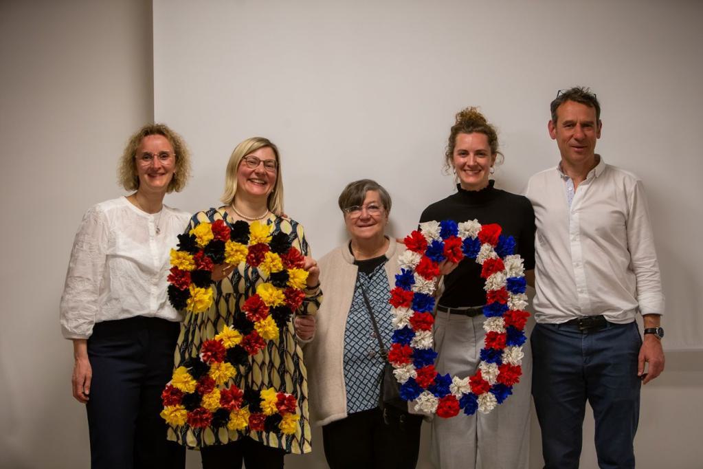 Fünf Personen schauen in die Kamera und halten eine aus Papierblumen gestaltete 20 in die Höhe