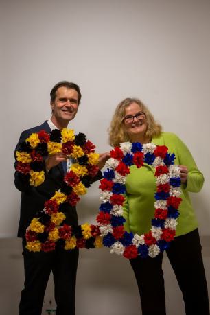 Ein Mann und eine Frau halten eine aus Papierblumen gestaltete 20 in den Händen