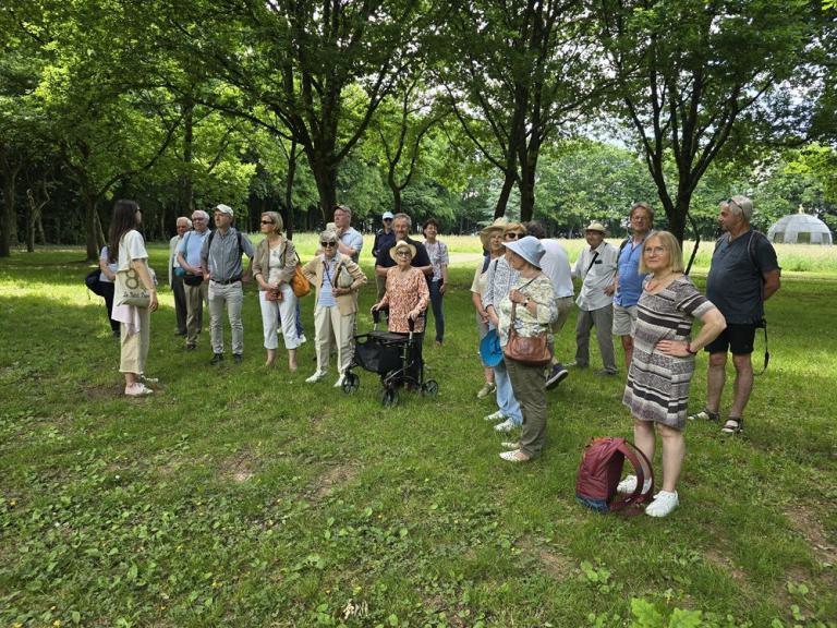 Die Teilnehmergruppe steht im Park und hört den Erzählungen der Führerin zu.
