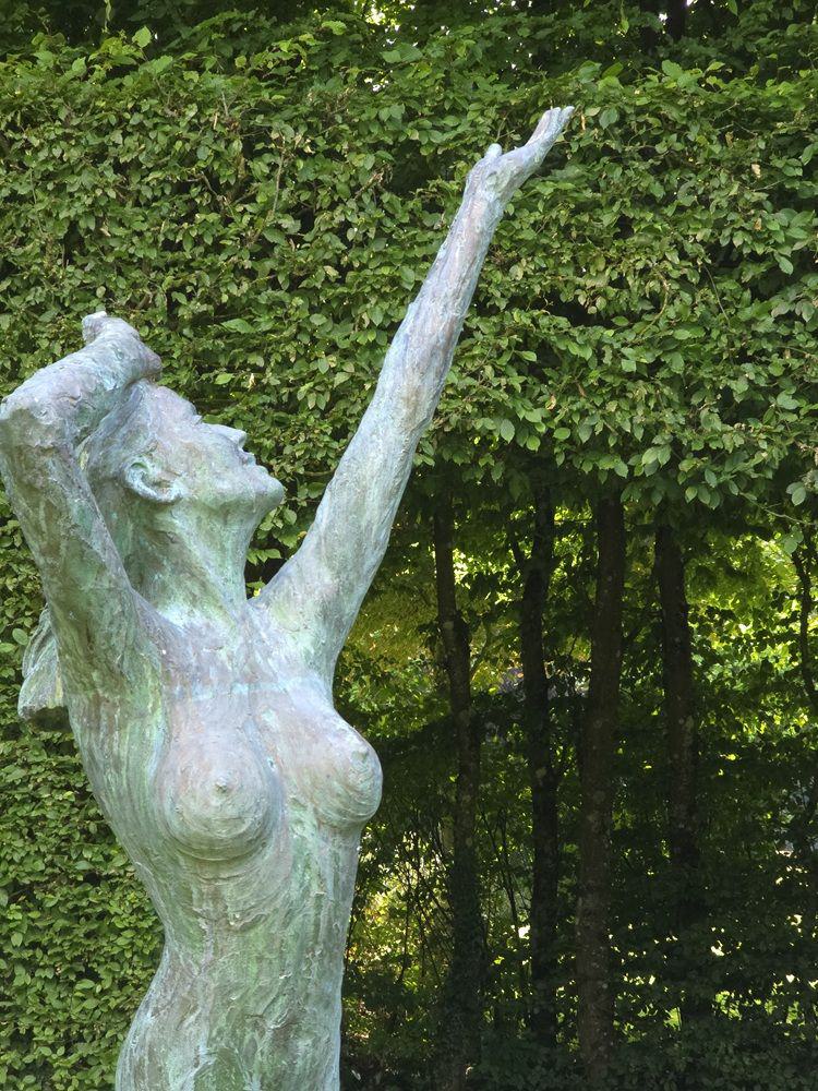 Eine Skulptur zeigt eine nackte Frau mit himmelwärts gestreckten Armen