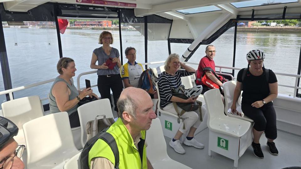 Eine Gruppe von Personen und Rädern auf einer Fähre bei der Überfahrt über die Seine