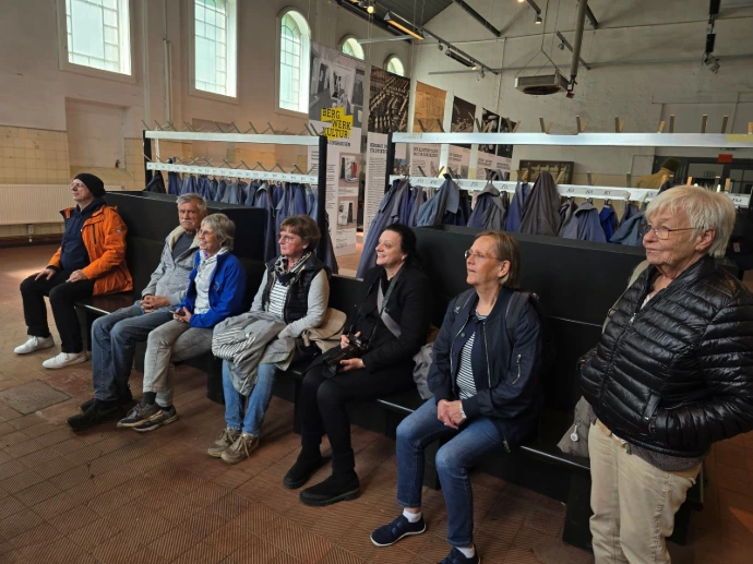 Die Besucher sitzen auf Bänken in der Waschkaue