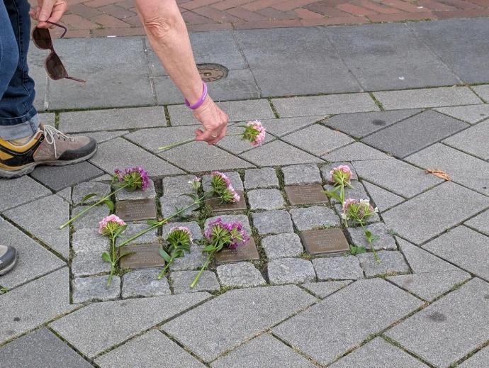 Eine Gruppe von Stolpersteinen wird gerade mit Blumen dekoriert